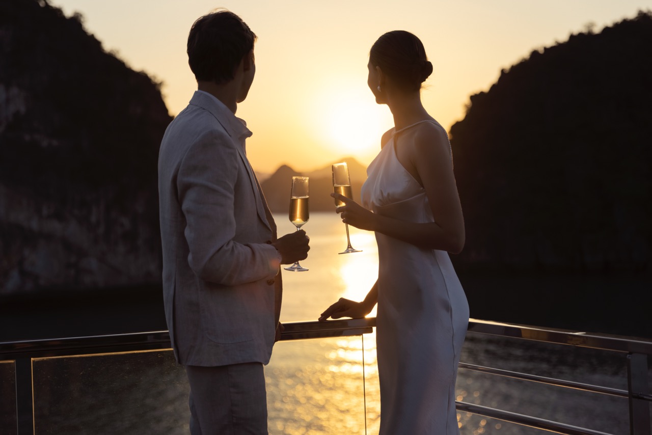 Romantic couple at sunset enjoying champagne on a cruise in Vietnam, honeymoon, Love, luxury travel.