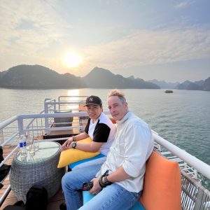 Couple relax at sunset on cushioned sundeck sofas.
