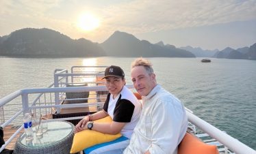 Sunset cruise on Lan Ha Bay featuring a couple enjoying the scenic view from the boat deck, capturin.
