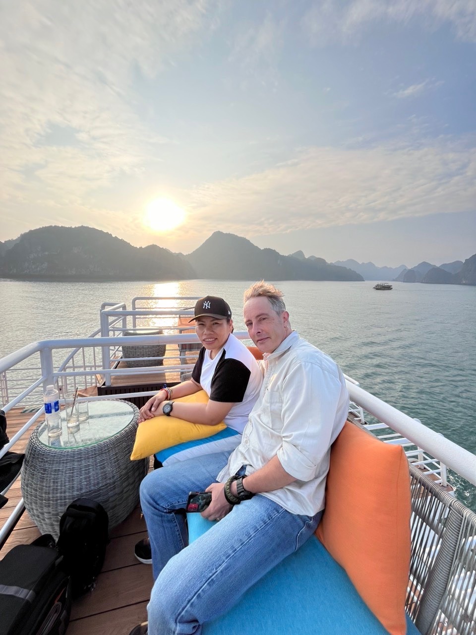 Sunset cruise on Lan Ha Bay featuring a couple enjoying the scenic view from the boat deck, capturin.
