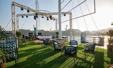 Scenic sunset view from the cruise balcony with seating and stage setup in Halong Bay. Perfect for r.