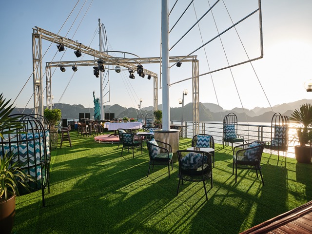 Scenic sunset view from the cruise balcony with seating and stage setup in Halong Bay. Perfect for r.