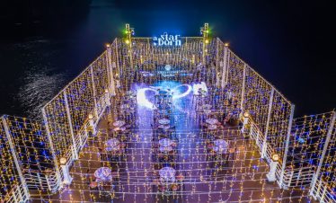 Stunning night scene of a luxury cruise deck illuminated with string lights, overlooking Halong Bay,.