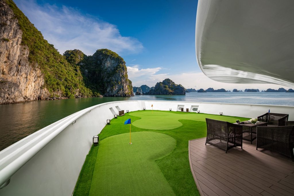 Enjoy luxury yacht with a mini golf course on deck amid stunning island scenery. Perfect for relaxation and leisure.