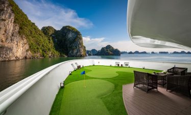 Enjoy luxury yacht with a mini golf course on deck amid stunning island scenery. Perfect for relaxation and leisure.