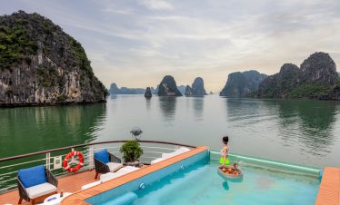 Stunning view of Halong Bay with calm waters and limestone karsts from a cruise balcony.