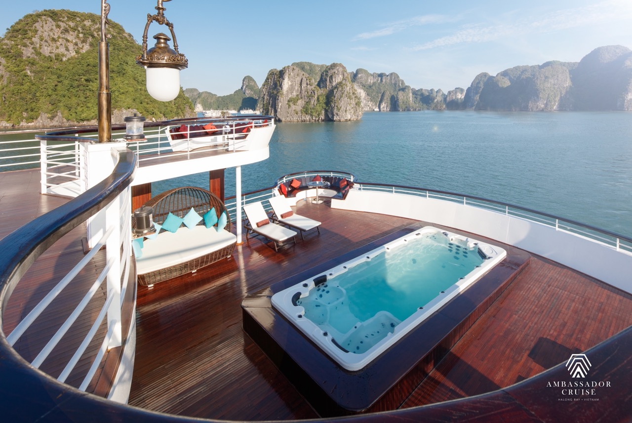 Luxurious cruise balcony overlooking Halong Bay with scenic limestone karsts and calm waters.