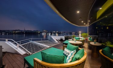 Scenic view of Lan Ha Bay from a cruise balcony with comfortable seating and vibrant cushions, captu.