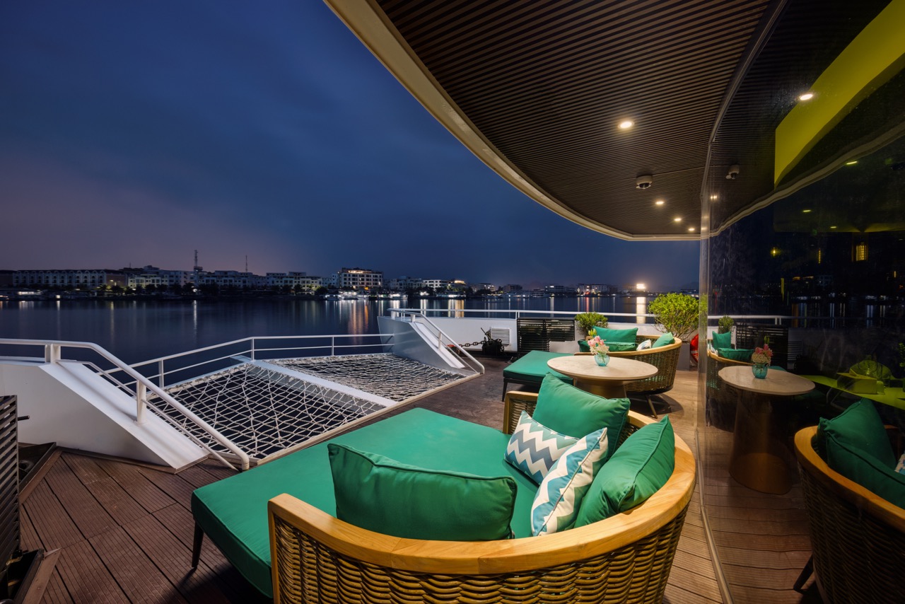 Scenic view of Lan Ha Bay from a cruise balcony with comfortable seating and vibrant cushions, captu.