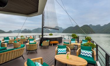 Stunning view from cruise balcony overlooking Lan Ha Bay with comfortable seating and lush scenery.