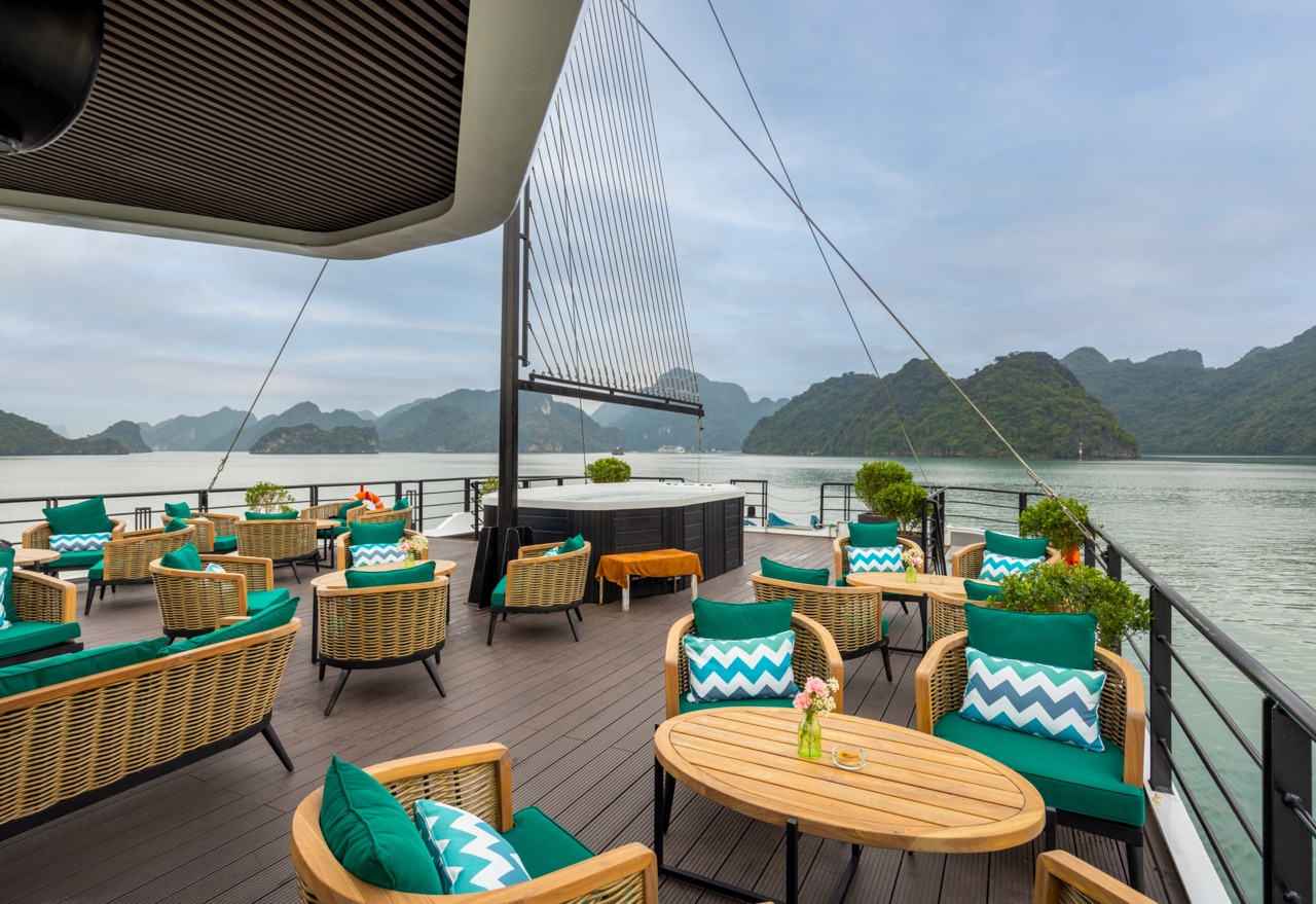 Stunning view from cruise balcony overlooking Lan Ha Bay with comfortable seating and lush scenery.