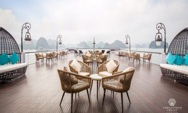 Stunning view from cruise balcony in Halong Bay with modern seating and scenic limestone karsts.