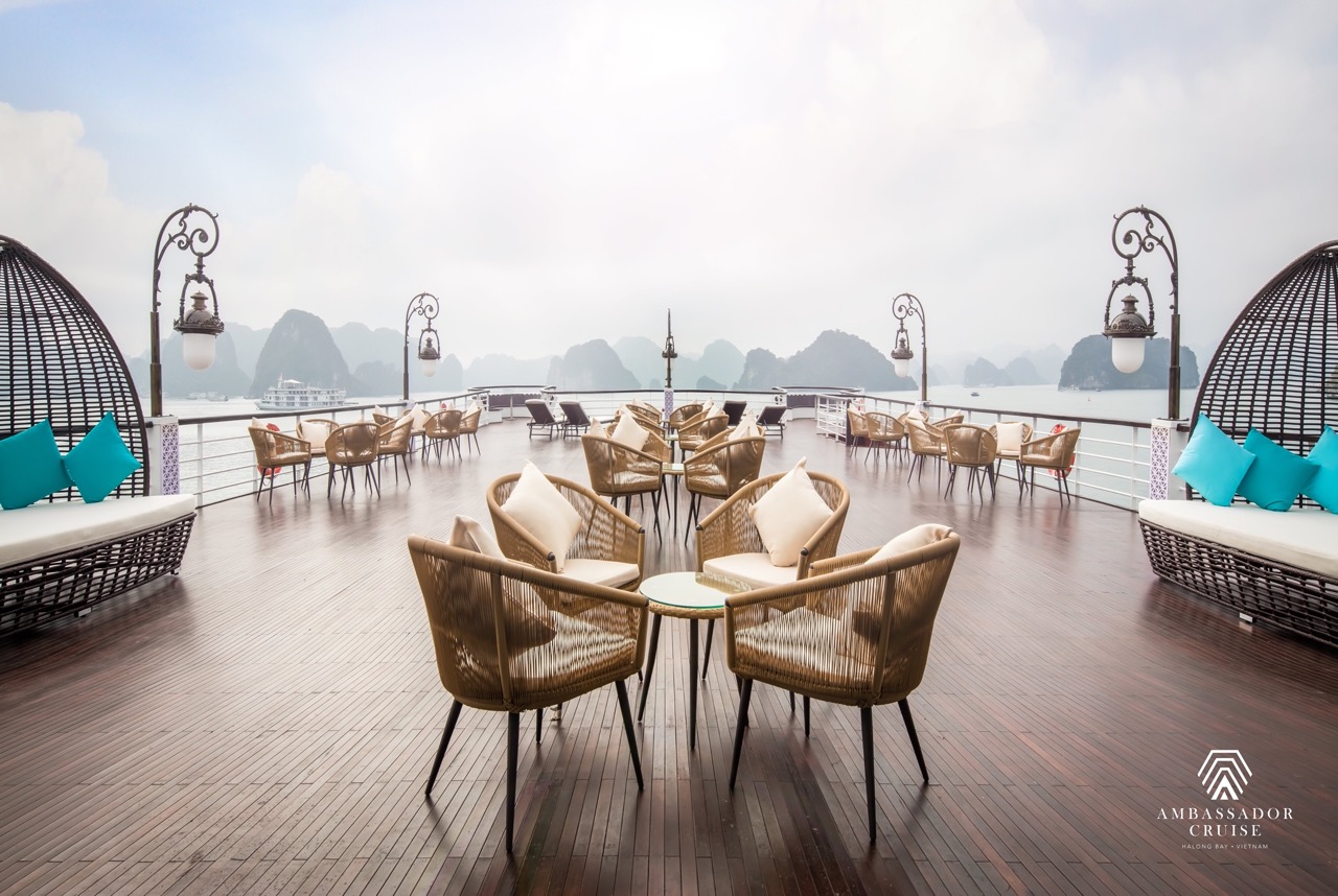 Stunning view from cruise balcony in Halong Bay with modern seating and scenic limestone karsts.