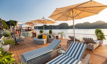 Relaxing lounge area on Serenity Cruise in Lan Ha Bay with sunbeds, umbrellas, and scenic water view.