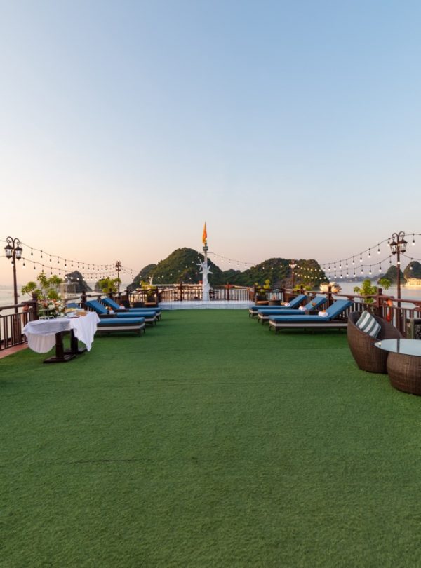 Breathtaking view of a cruise deck with lounge chairs overlooking Ha Long Bay, Vietnam.