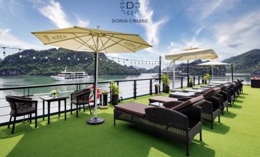 Stunning Halong Bay cruise balcony with panoramic views, luxurious seating, and vibrant natural scen.