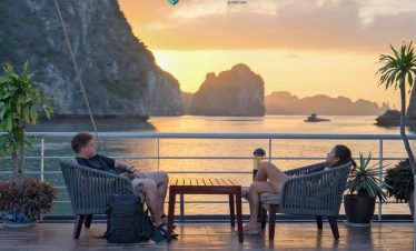 Relaxing on a cruise balcony in Halong Bay at sunset, enjoying stunning limestone karsts and tranqui.
