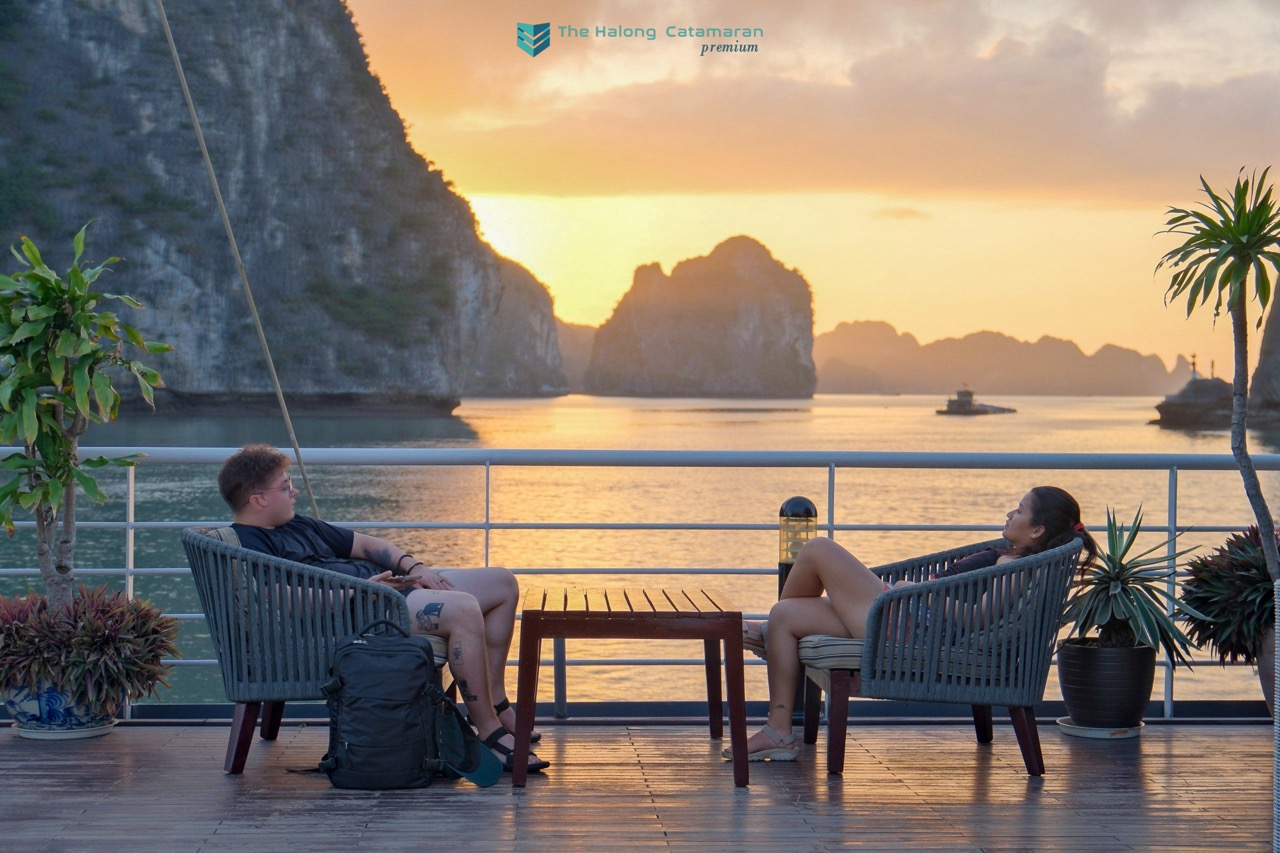 Relaxing on a cruise balcony in Halong Bay at sunset, enjoying stunning limestone karsts and tranqui.
