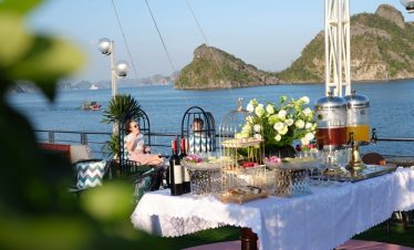 Beautiful scene of a luxurious cruise dining setup on Halong Bay with lush islands in the background.