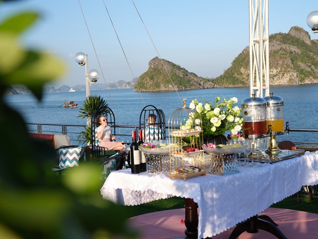 Beautiful scene of a luxurious cruise dining setup on Halong Bay with lush islands in the background.