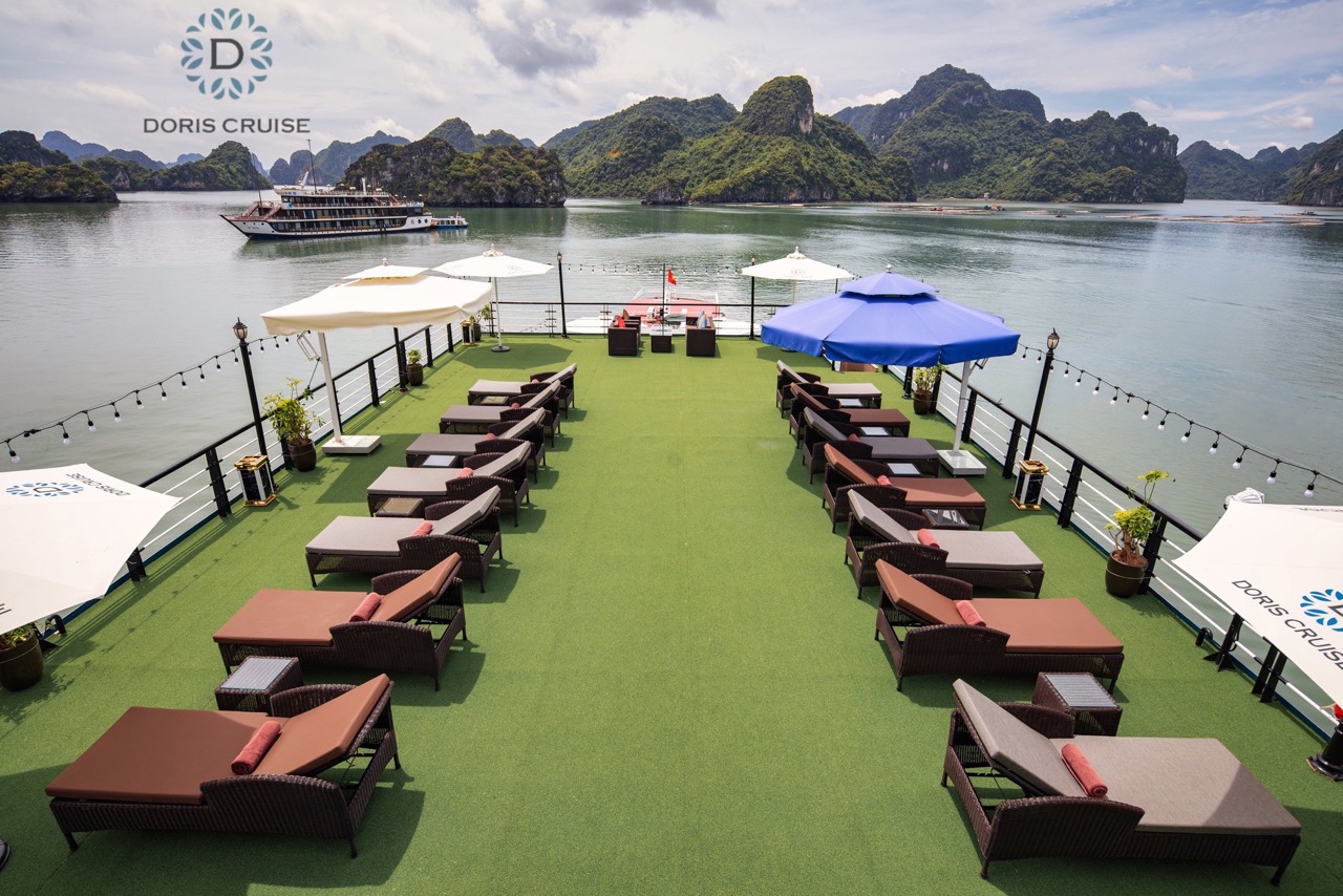 Relaxing cruise deck with loungers overlooking Halong Bay's stunning limestone karsts - ViettrendTou.