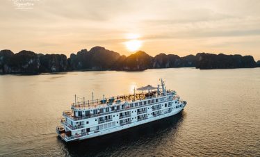 A scenic view of a luxury cruise sailing through Halong Bay at sunset, showcasing stunning limestone.