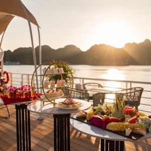 Sunset party with cakes, fruit, and tea on deck.