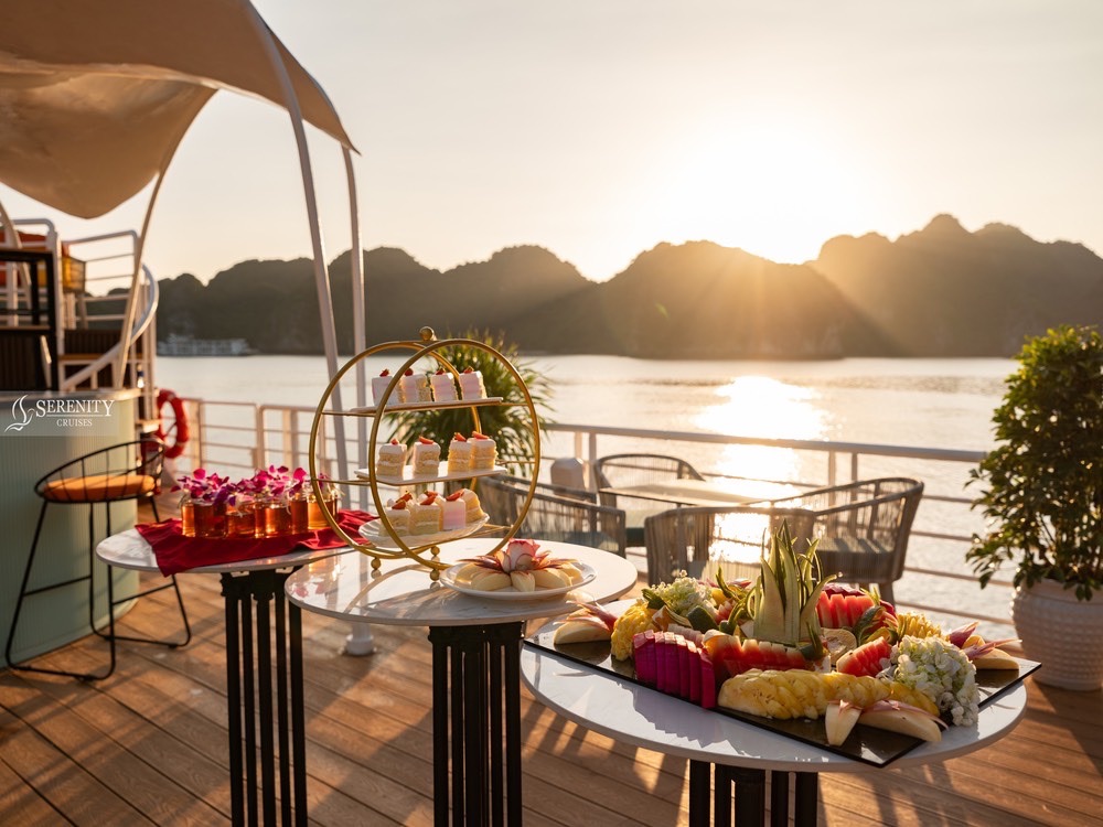 Beautiful scene of a luxurious cruise deck with a sunset view over Lan Ha Bay, featuring a table set.