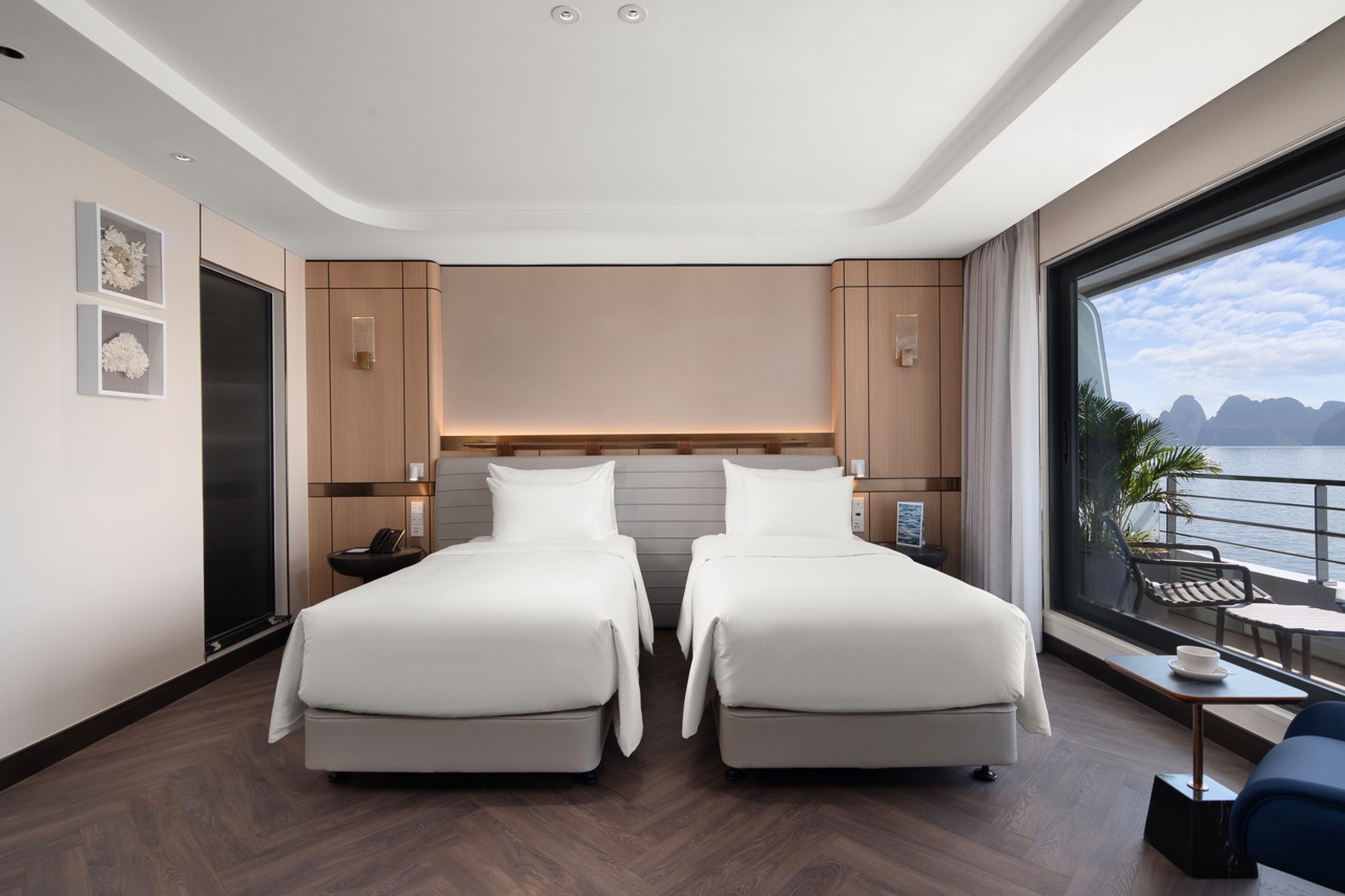 Modern hotel room with sea view, twin beds, balcony, and contemporary decor for a luxury Vietnam vacation.