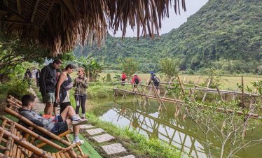 Scenic scene of tourists enjoying a cruise balcony in Halong Bay with lush mountains and tranquil wa.