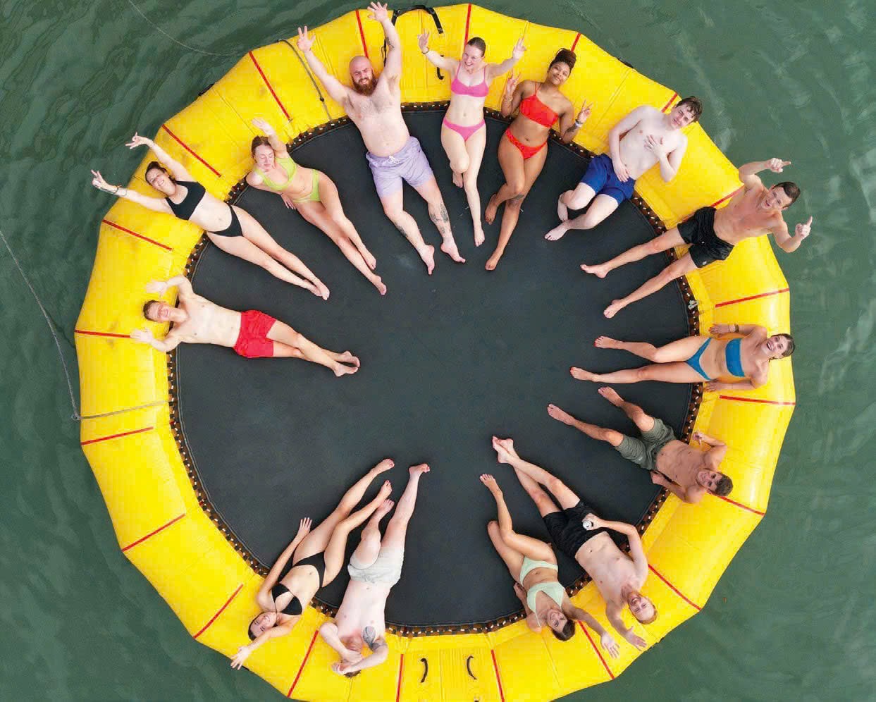 People relaxing on a floating trampoline in Lan Ha Bay, Vietnam, enjoying a sunny day and scenic vie.