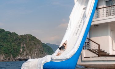 Luxury Halong Bay cruise balcony with water slide, scenic seascape, and relaxing atmosphere.