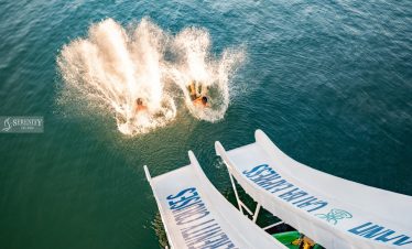 Scenic view of Halong Bay with people jumping into the water from a cruise balcony, vibrant and adve.