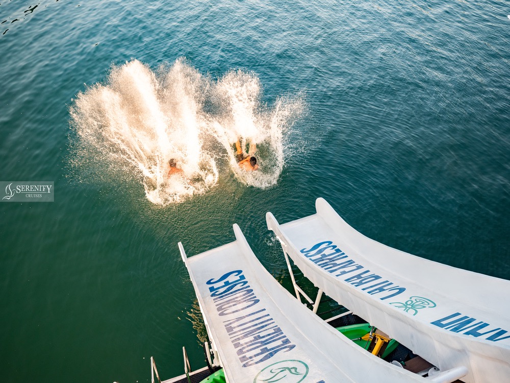Scenic view of Halong Bay with people jumping into the water from a cruise balcony, vibrant and adve.