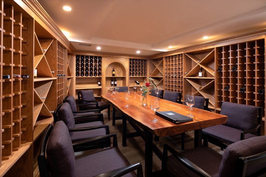 Cozy private wine tasting room with wooden wine racks and a polished wooden table.