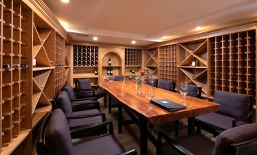 Cozy private wine tasting room with wooden wine racks and a polished wooden table.