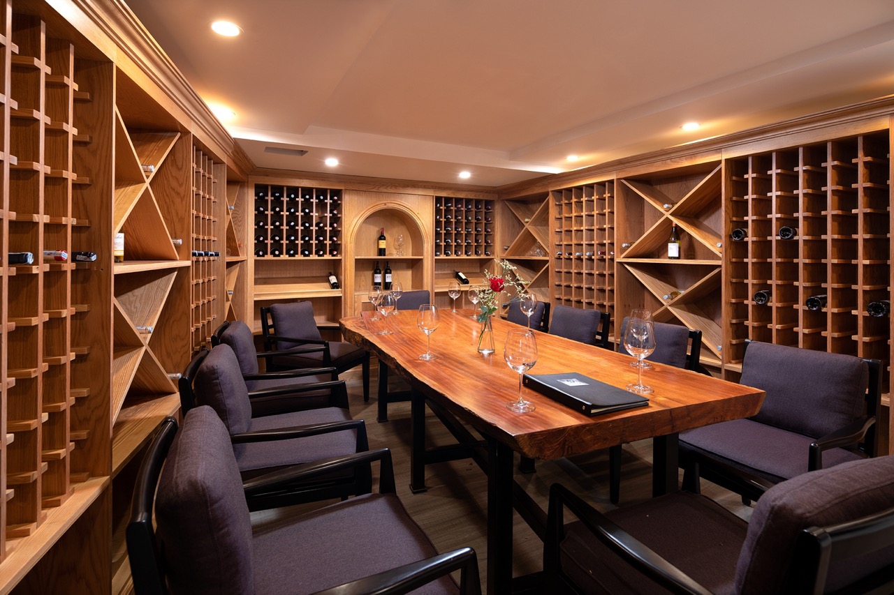 Cozy private wine tasting room with wooden wine racks and a polished wooden table.