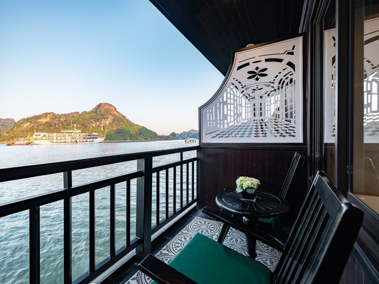 Stunning view from a luxury cruise balcony in Halong Bay, showcasing emerald waters and limestone ka.