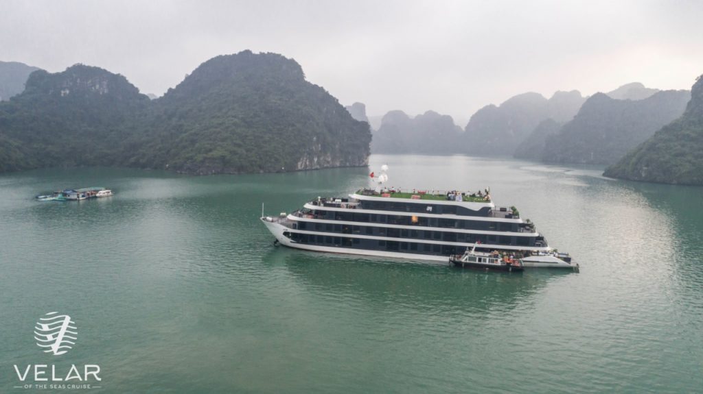 Cruise ship sailing through scenic Halong Bay with limestone karsts and emerald waters.