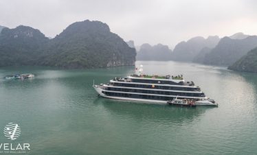 Cruise ship sailing through scenic Halong Bay with limestone karsts and emerald waters.