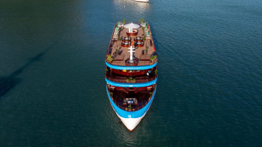 Aerial view of a luxurious cruise boat sailing through Halong Bay's emerald waters, showcasing sceni.