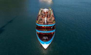 Aerial view of a luxurious cruise boat sailing through Halong Bay's emerald waters, showcasing sceni.