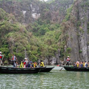 Relaxing boat tour in Ha Long Bay with tourists and scenic limestone cliffs.