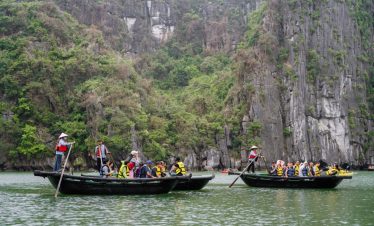 Relaxing boat tour in Ha Long Bay with tourists and scenic limestone cliffs.