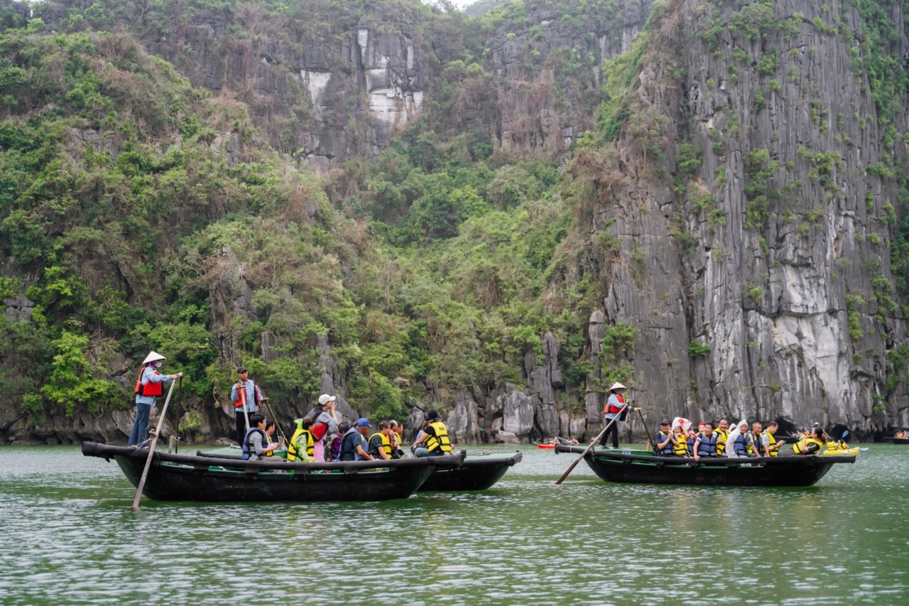 Relaxing boat tour in Ha Long Bay with tourists and scenic limestone cliffs.
