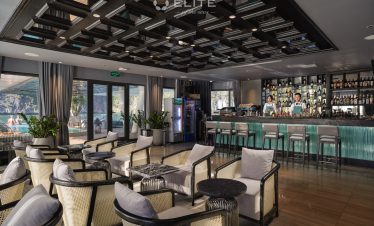 Relaxing cruise lounge with modern decor and panoramic windows overlooking Halong Bay.