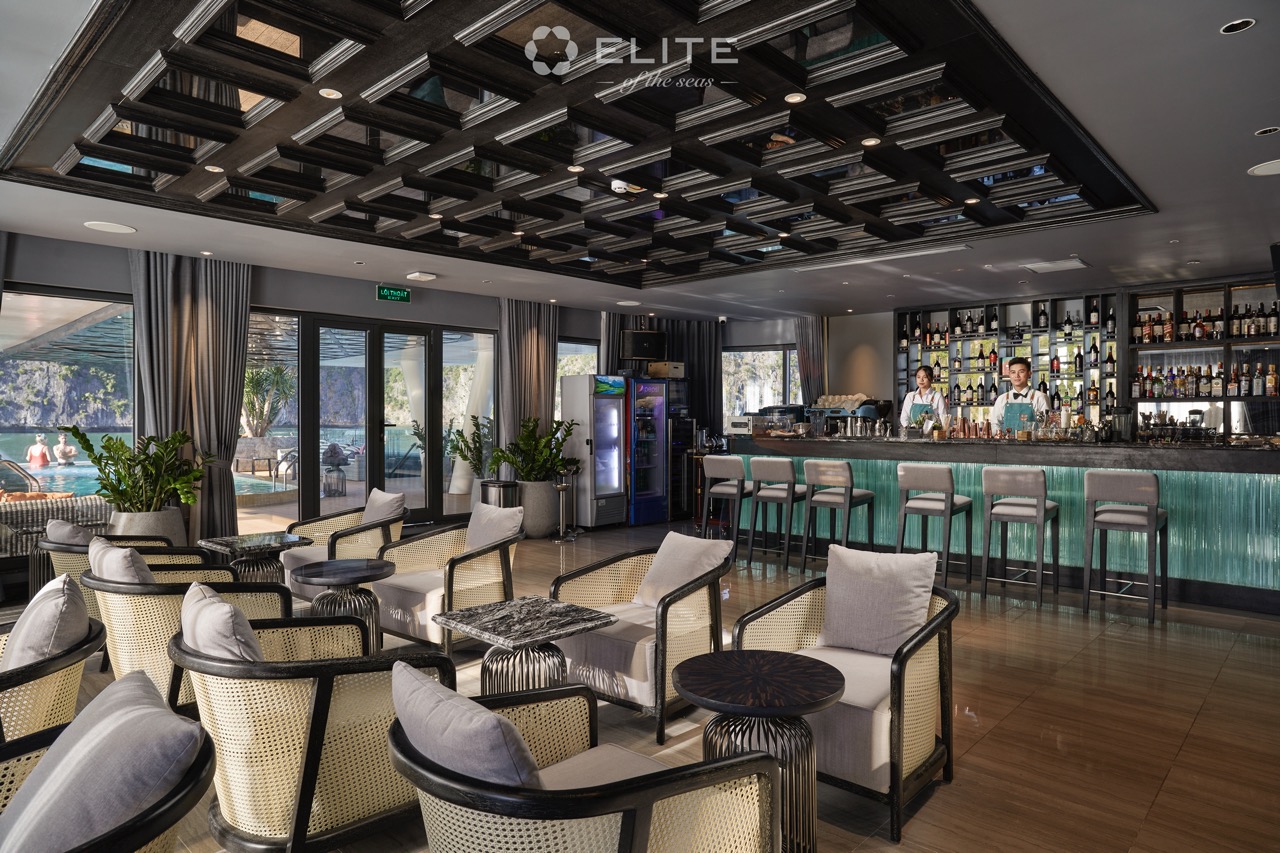 Relaxing cruise lounge with modern decor and panoramic windows overlooking Halong Bay.