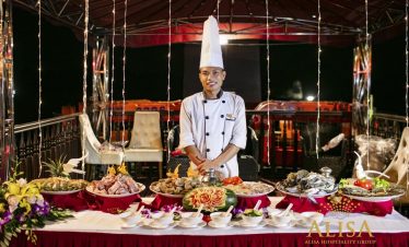 Elegant cruise dining scene with a chef preparing seafood on a luxurious boat in Halong Bay, showcas.