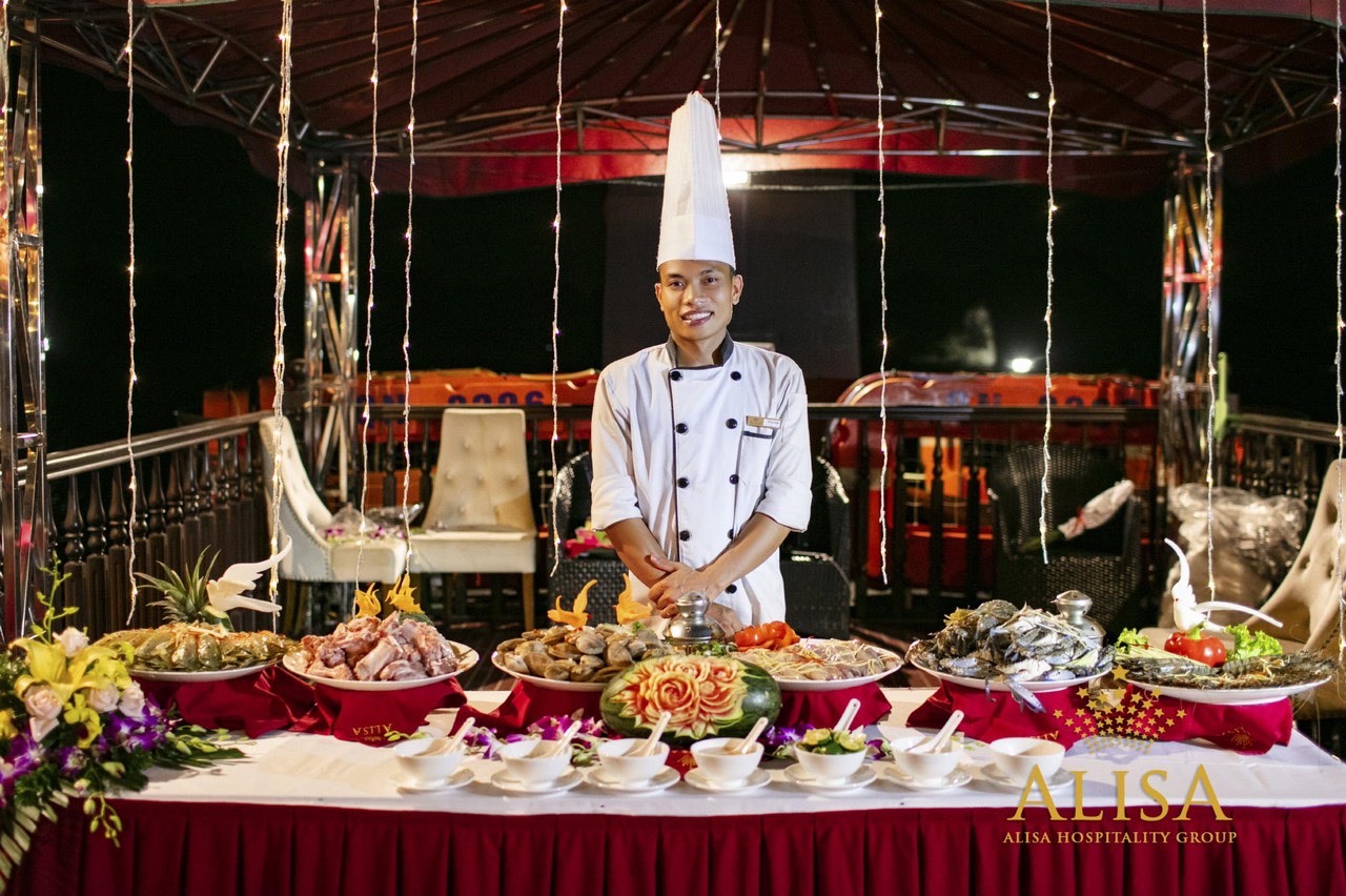 Elegant cruise dining scene with a chef preparing seafood on a luxurious boat in Halong Bay, showcas.