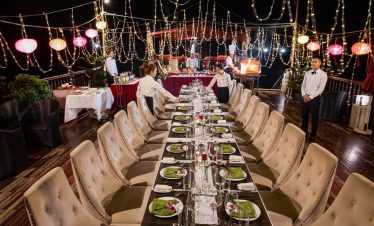 Dinner table on Halong Bay cruise with elegant settings and string lights, perfect for a luxurious t.